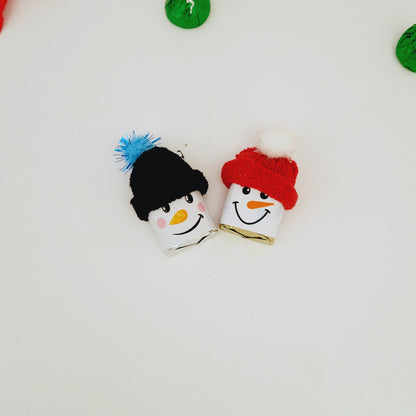 Two snowman-wrapped Hershey Nuggets with colorful hats on a white background