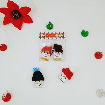 Packaged snowman-themed hair clips with decorative poinsettia flowers and Christmas ornaments on a white background.